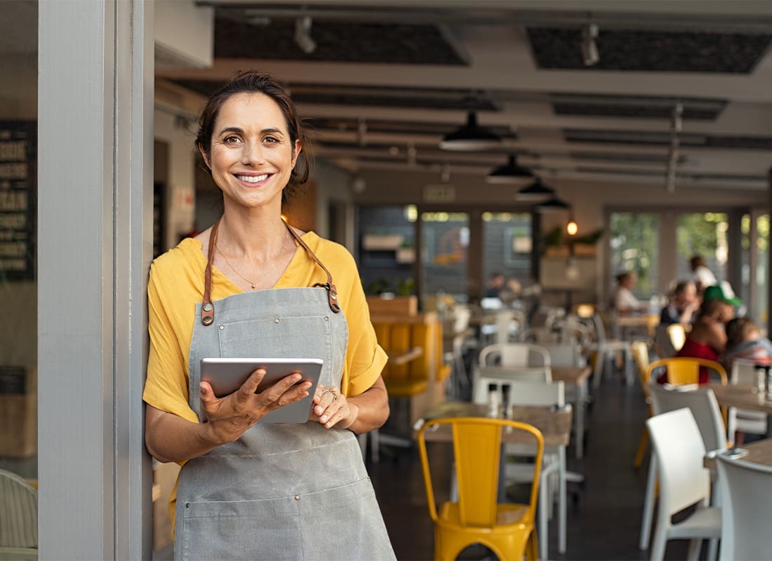 Insurance by Industry - Small Restaurant Owner Standing by the Door Holding a Tablet